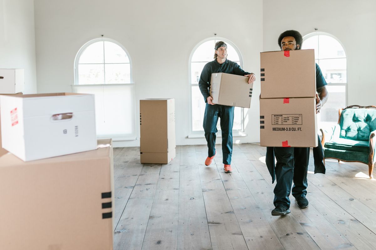 Personal de mudanza cargando cajas en una casa